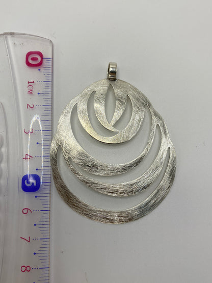 Reverso del dije en escala de precisión mostrando el peso de 5.7 g y el marca de plata .925