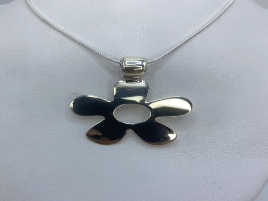 Dije de plata calado de cinco pétalos, 3 cm, colgando de cadena de plata sobre fondo blanco