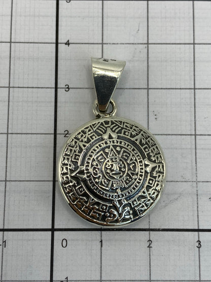 Dije calendario azteca en la mano mostrando su tamaño de 3.5 cm de diámetro