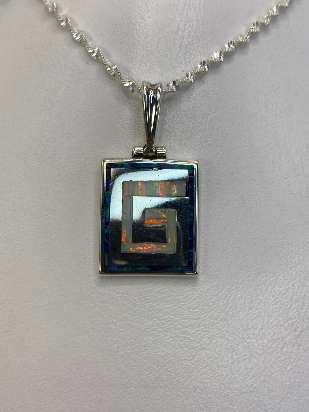 Dije de plata 950 con ópalo de fuego blanco en diseño geométrico cuadrado, colgado en cadena de plata