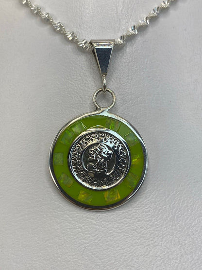 Vista lateral del dije de 3.5 cm con moneda tallada en plata 925, mostrando el engaste de la piedra