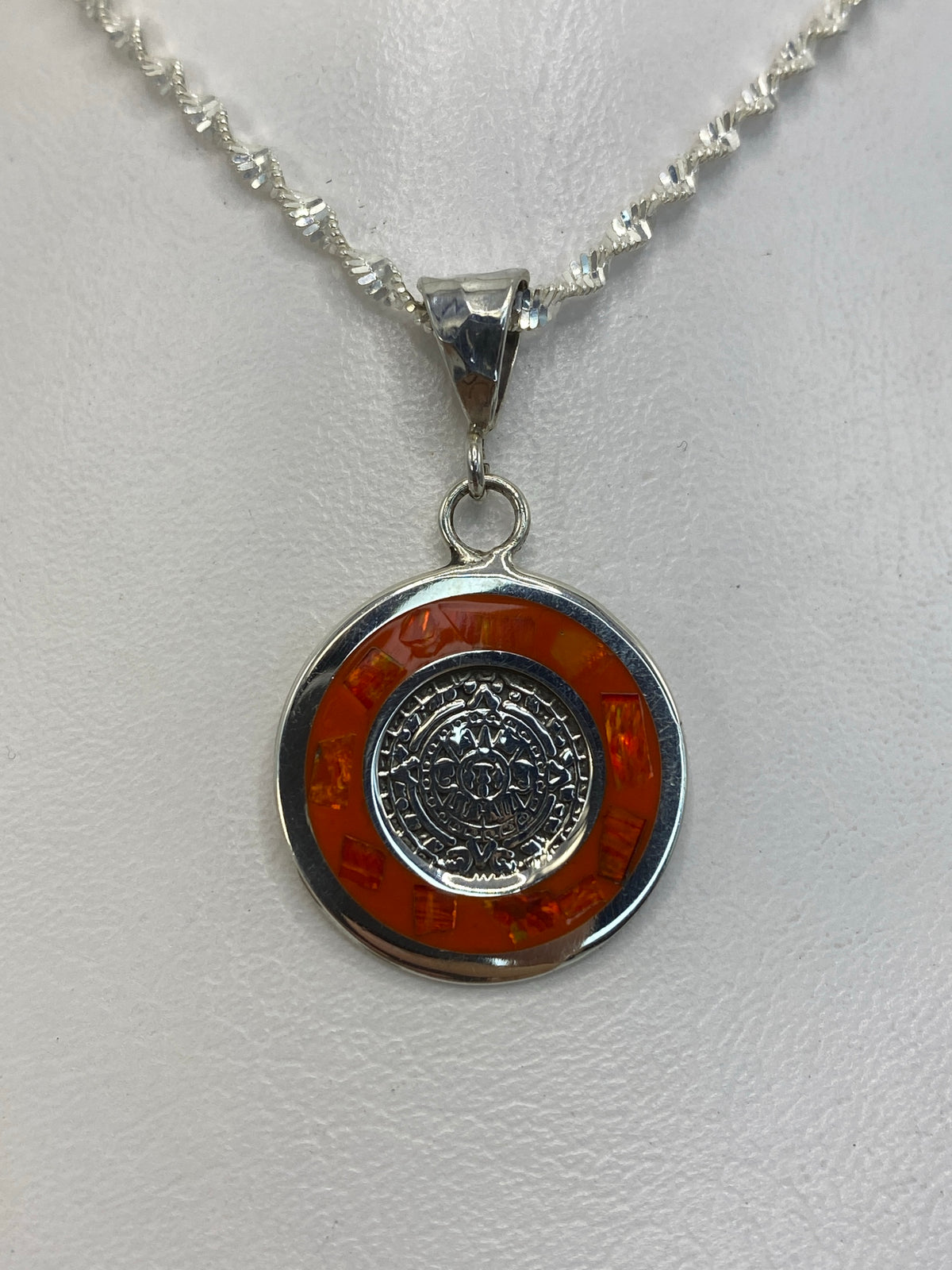 Dije de plata con rueda maya y ópalo de fuego naranja colgando de una cadena de plata