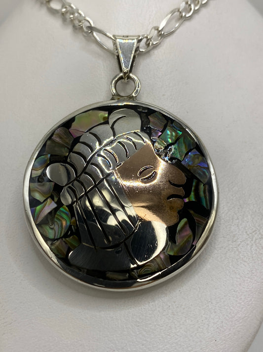 Dije de plata 925 prehispánico con rostro de guerrero de perfil, tocado de plumas grabadas y fondo de nácar iridiscente