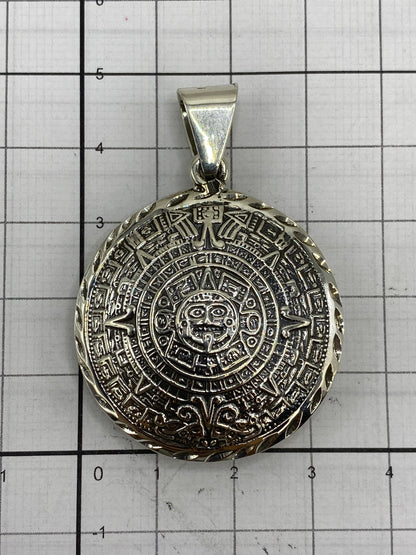 Dije del Calendario Azteca sobre medidor de referencia — 5 cm de largo × 3.5 cm de ancho