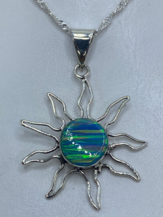 Dije de plata 925 en forma de sol con ópalo de fuego azul en el centro