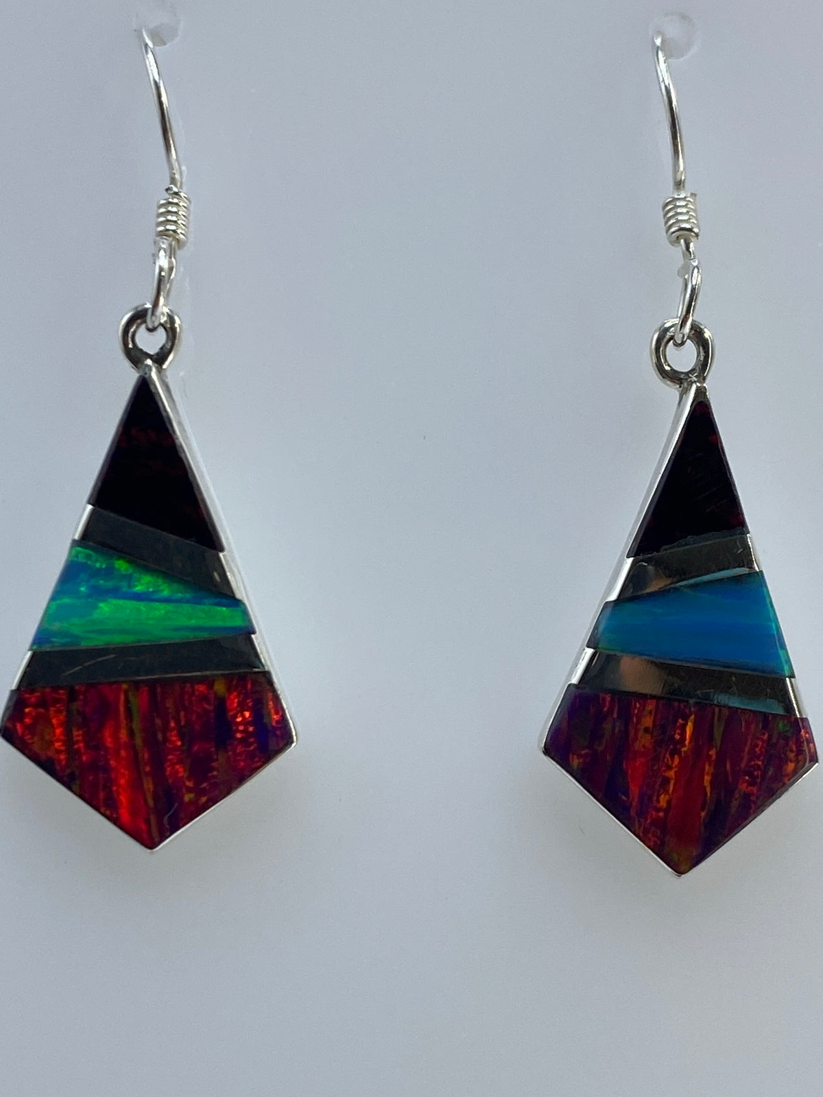 Aretes colgando mostrando los tonos rojo, azul, verde y amarillo del ópalo
