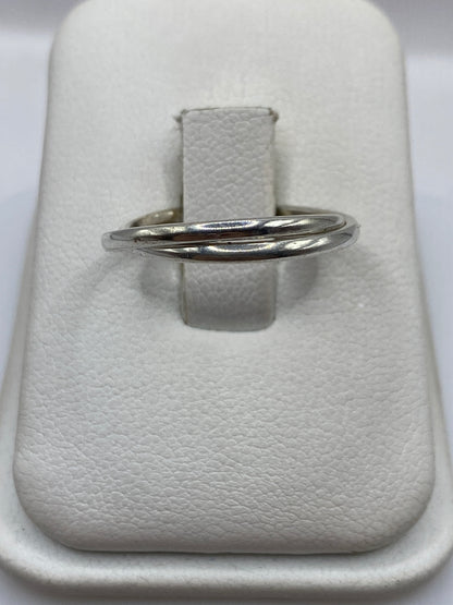 Anillo de plata banda doble pulida en la mano de una mujer, mostrando el brillo espejo