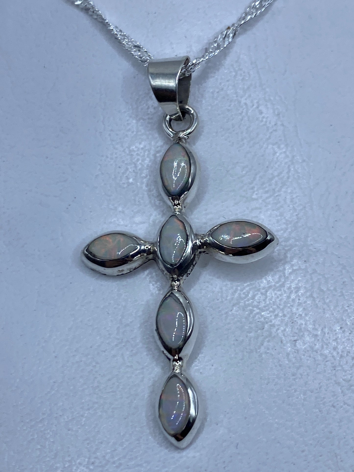 Dije cruz de plata .950 con ópalos de fuego multicolor, colgando de una cadena