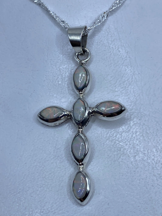 Dije cruz de plata .950 con ópalos de fuego multicolor, colgando de una cadena