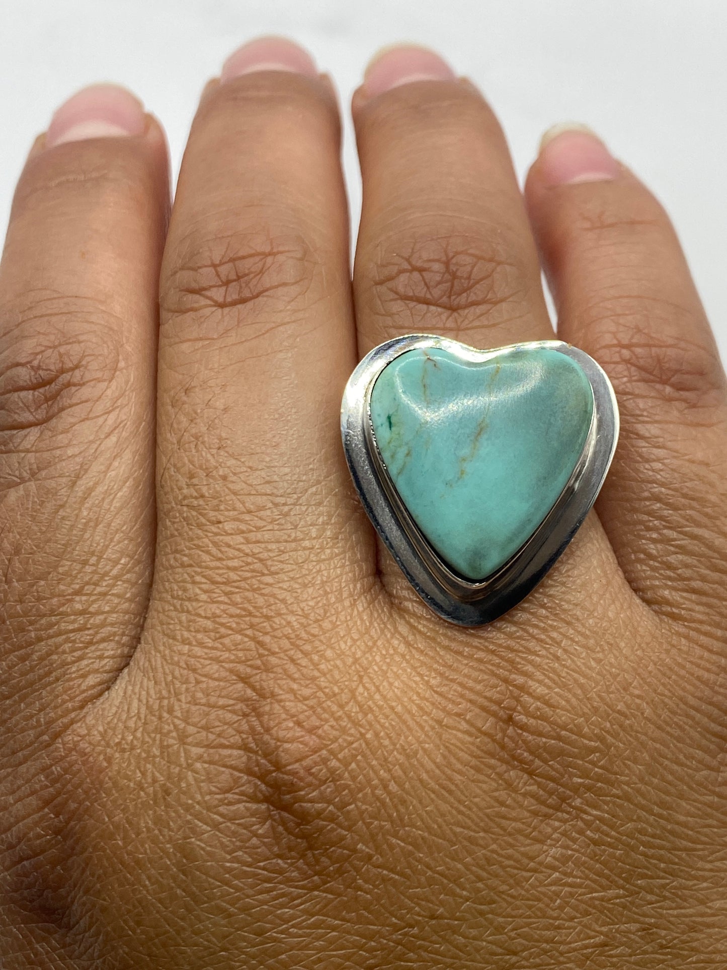 Anillo en mano de mujer mostrando el frente de turquesa y el pulido de la plata de Taxco