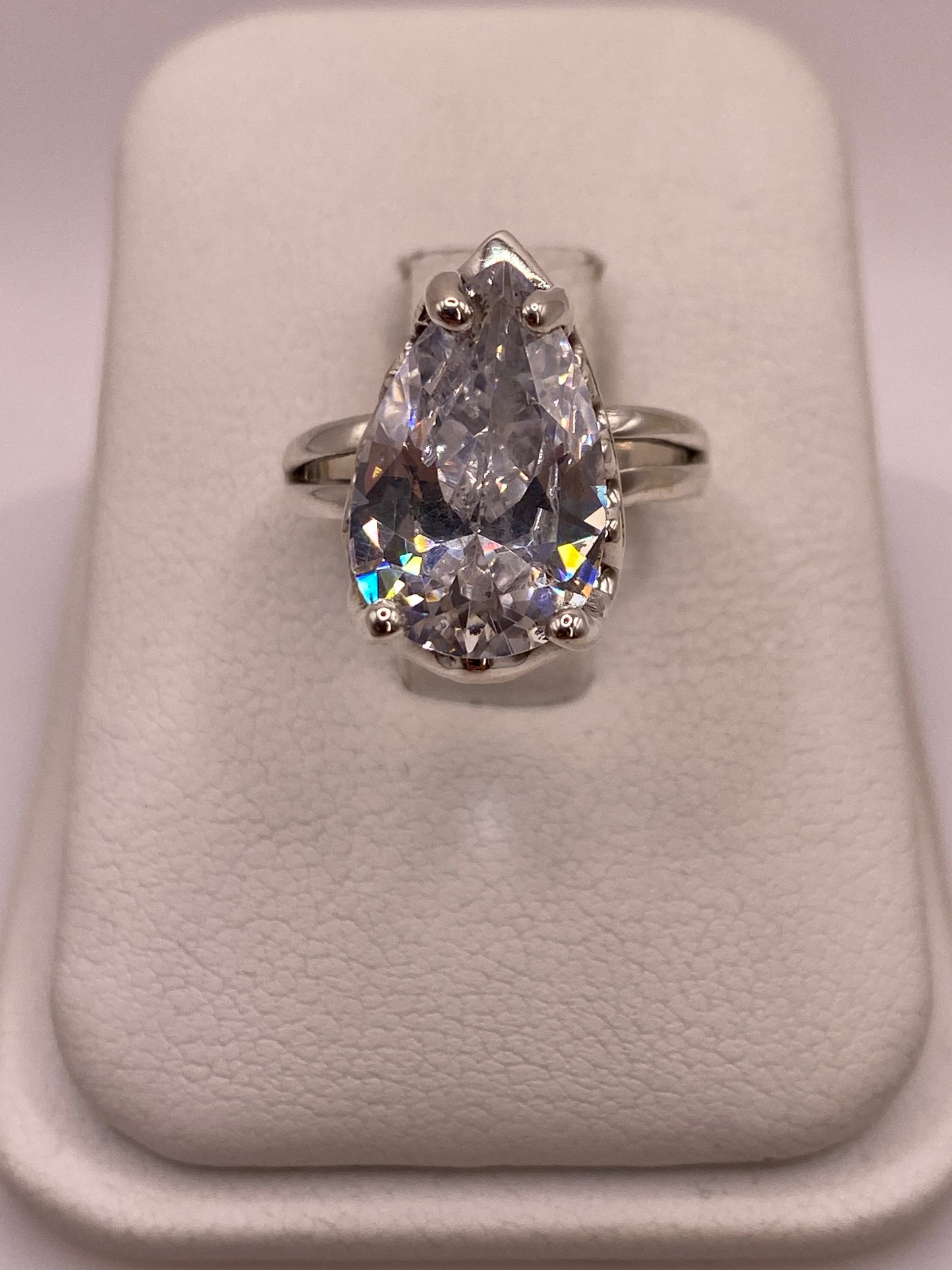 Anillo solitario de plata .925 con circonia pera blanca glacial vista desde arriba sobre portaanillos blanco