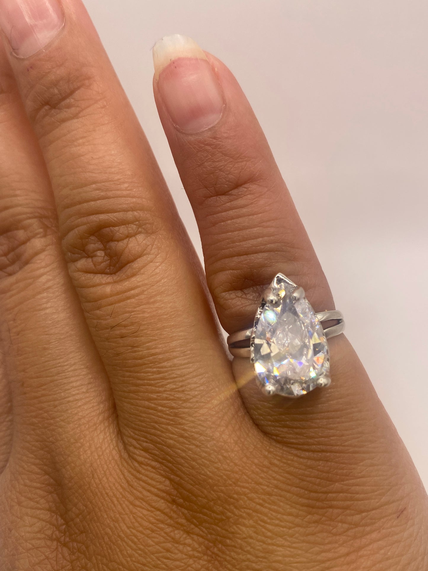 Anillo solitario plata .925 con circonia pera puesto en la mano de una mujer mostrando el aro dividido