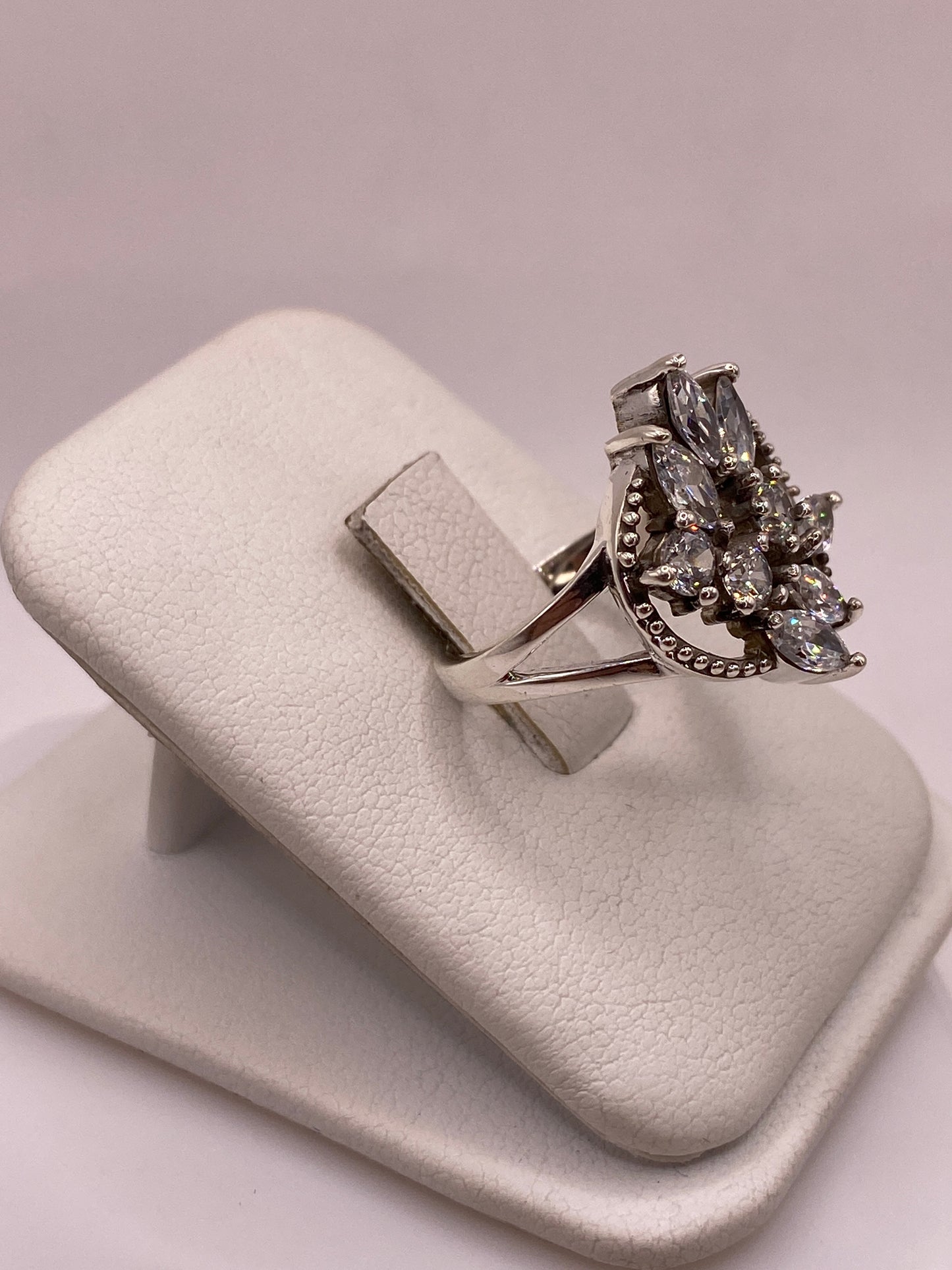 Vista lateral del anillo floral de plata .925 con circonias blancas mostrando la banda dividida y el marco milgrain de Taxco
