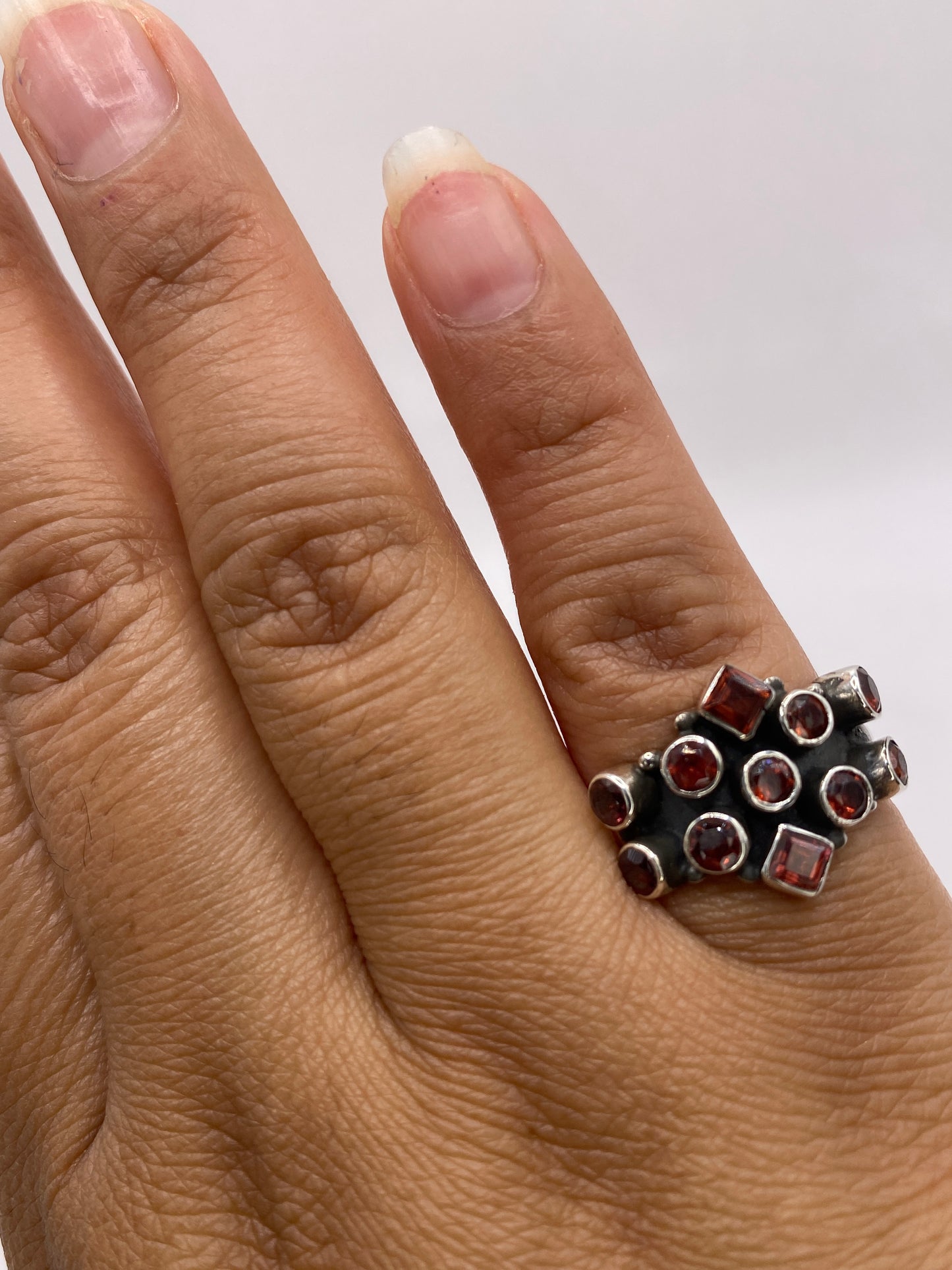 Anillo coctel de plata racimo circonia roja puesto en la mano de una mujer, mostrando proporción y color intenso