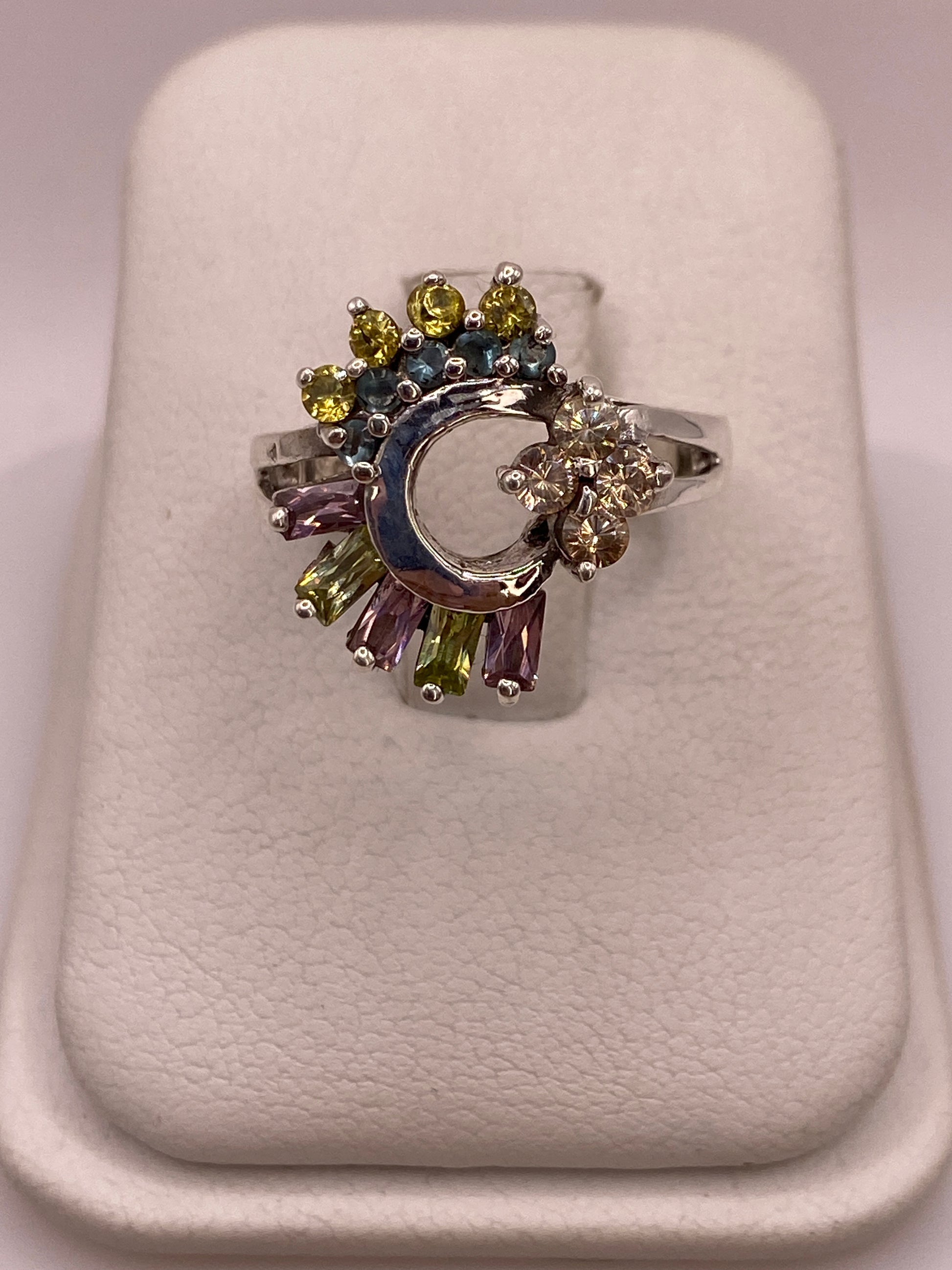 Anillo de plata .925 con luna creciente central y circonias multicolor amarillo-verde, azul, lila y champagne sobre base de exhibición blanca