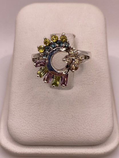 Anillo de plata .925 con luna creciente central y circonias multicolor amarillo-verde, azul, lila y champagne sobre base de exhibición blanca