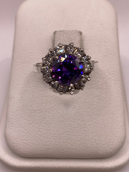 Anillo de plata .925 con circonia morada central y halo de circonias blancas sobre exhibidor blanco