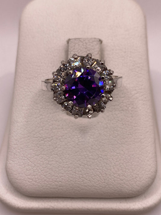 Anillo de plata .925 con circonia morada central y halo de circonias blancas sobre exhibidor blanco
