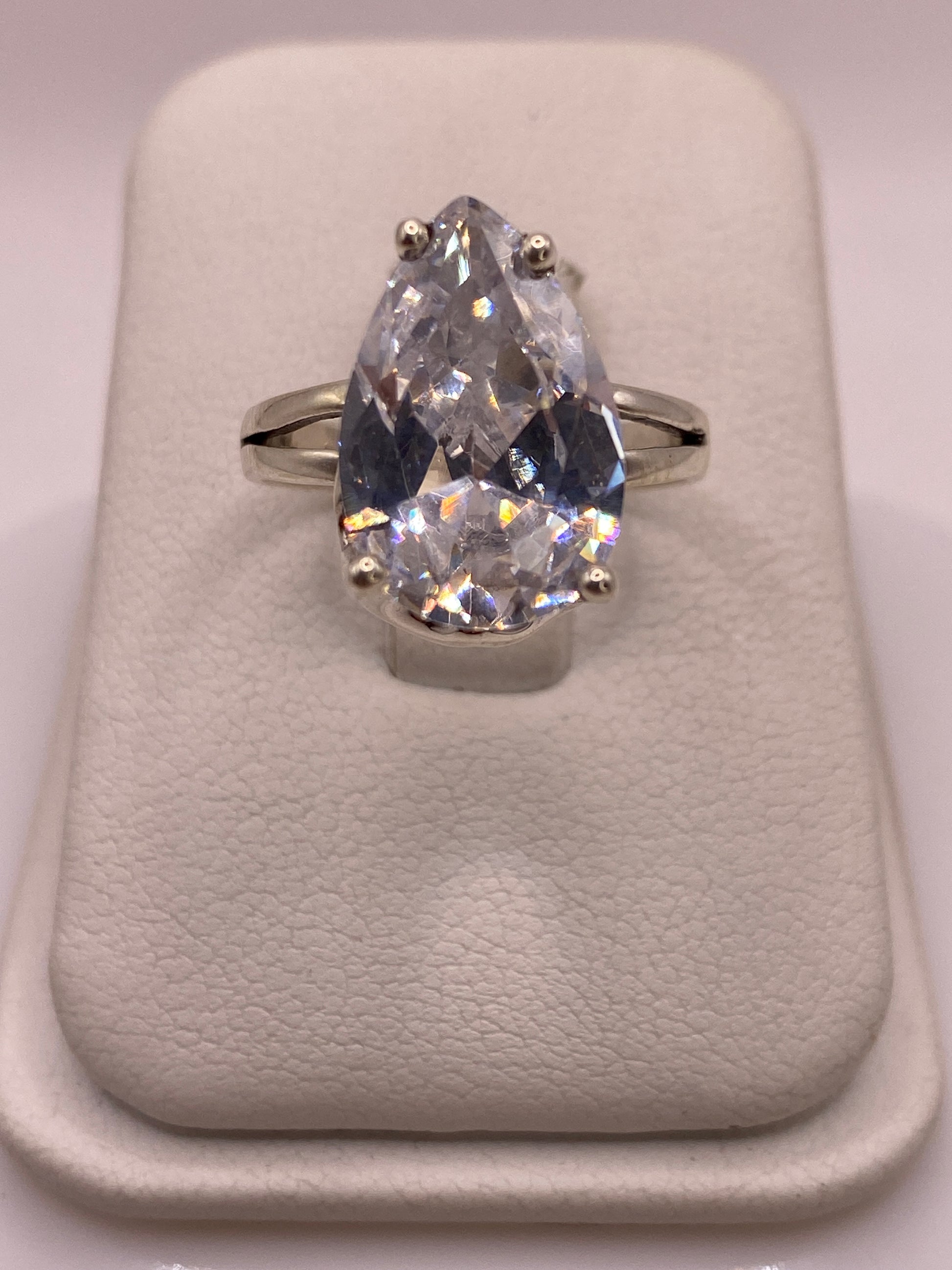 Anillo solitario de plata con circonia pera blanca en mano de mujer, brillo diamantado intenso
