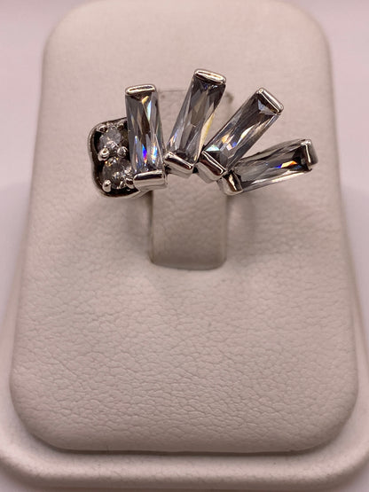 Anillo solitario de plata con circonia gris ahumado en talla baguette sobre dedo de mujer con manicura natural