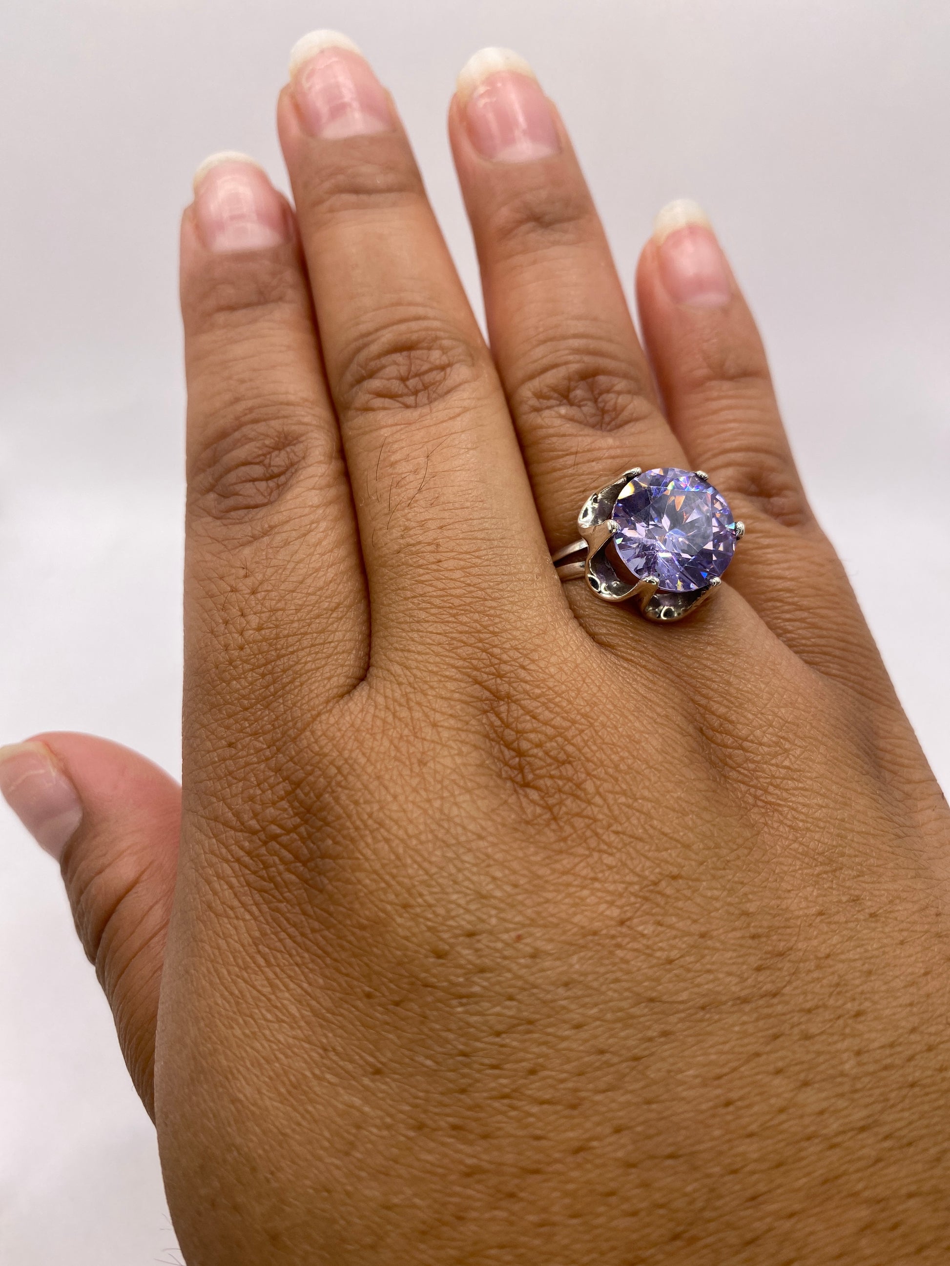 Anillo solitario en la mano de una mujer, mostrando el brillo y presencia de la circonia violeta