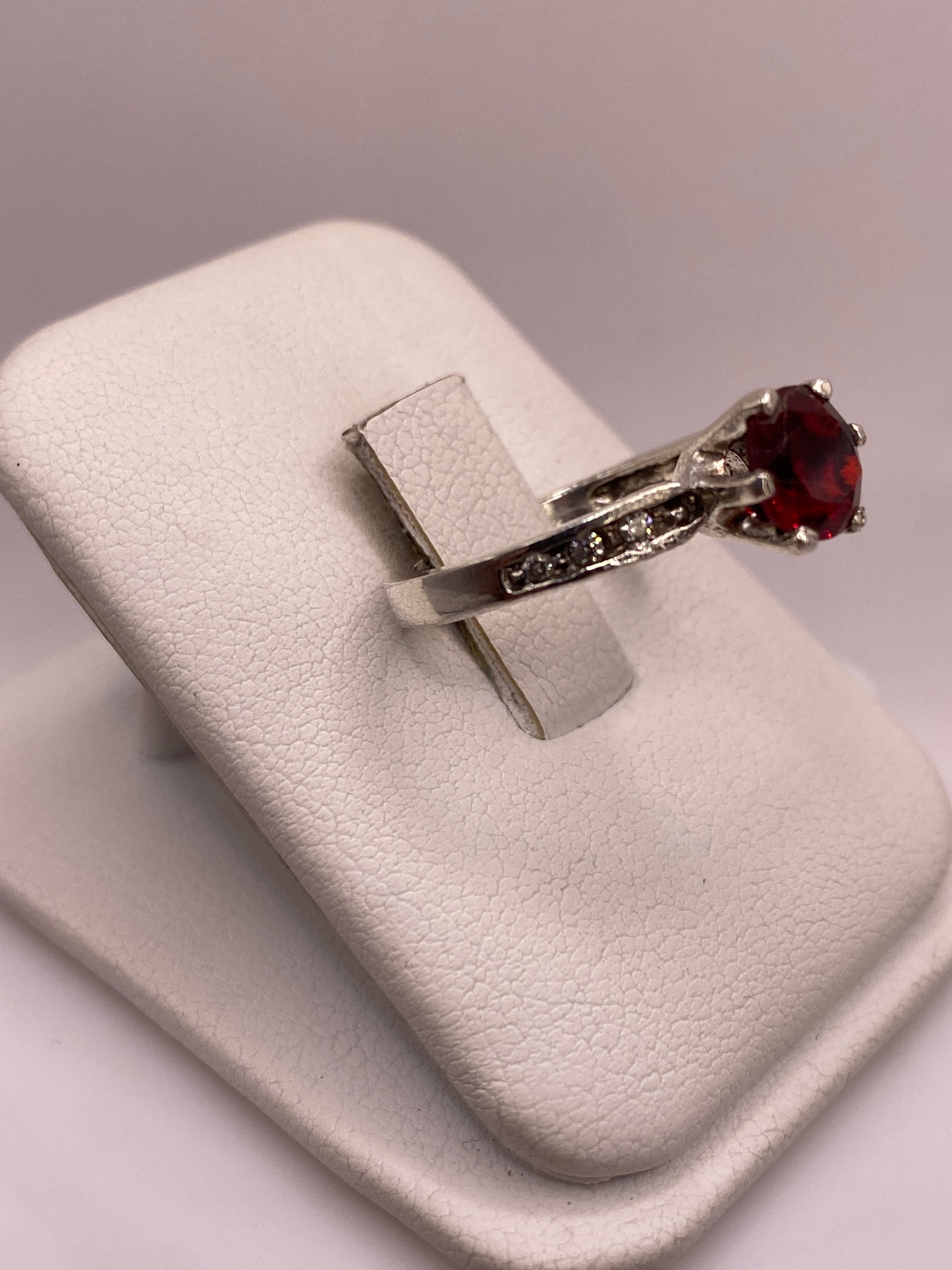 Vista frontal del anillo de plata .925 con circonia roja facetada, brillo de gema noble