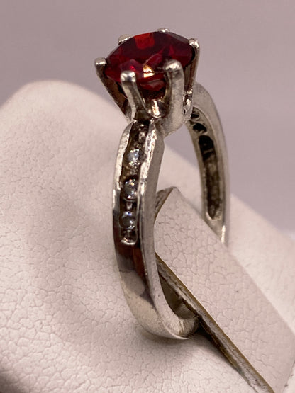 Anillo solitario en plata Taxco .925 sobre la mano de una mujer, circonia roja brillante