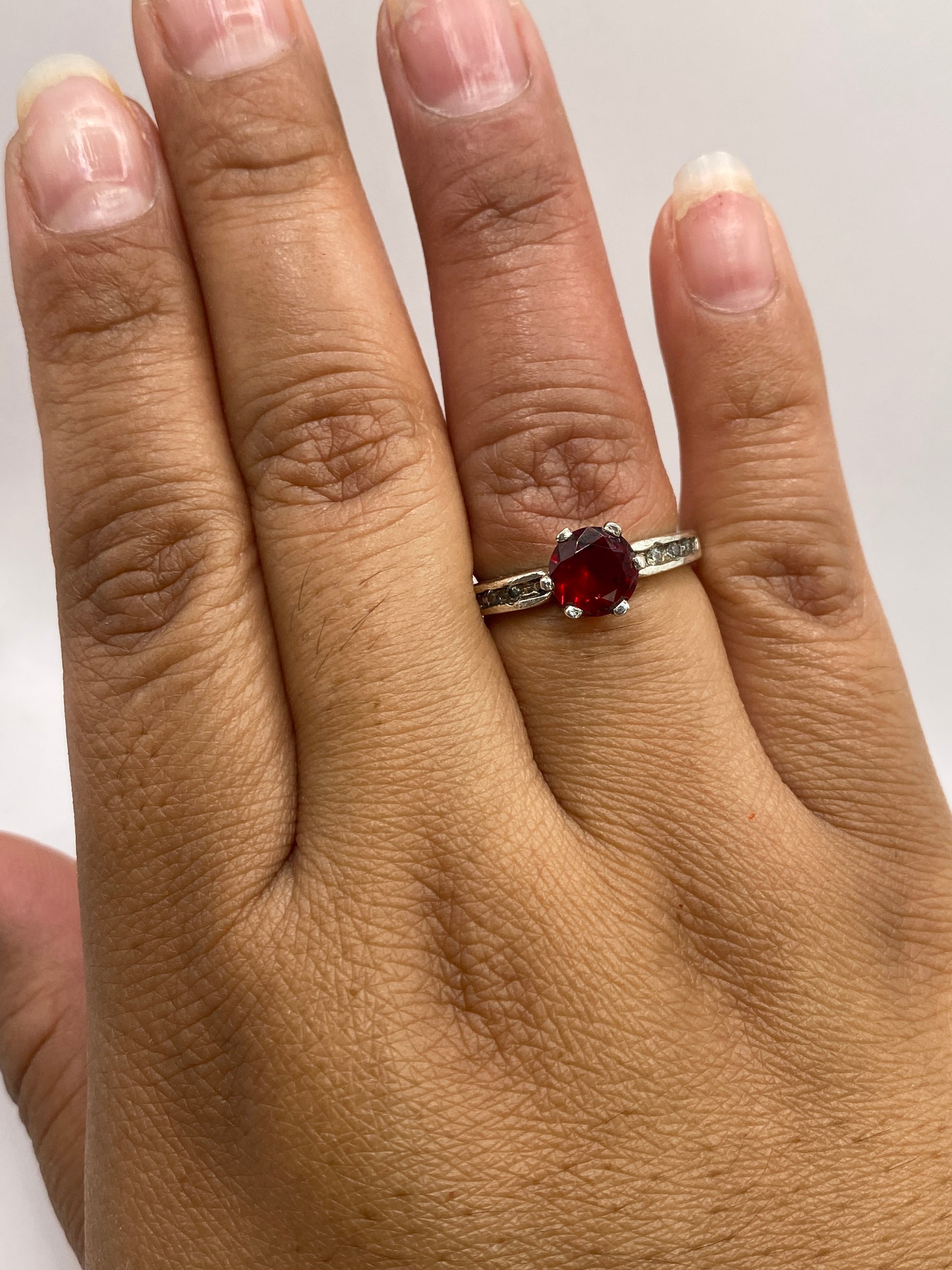 Detalle del engaste y prongs de plata asegurando la circonia roja en anillo de coctel