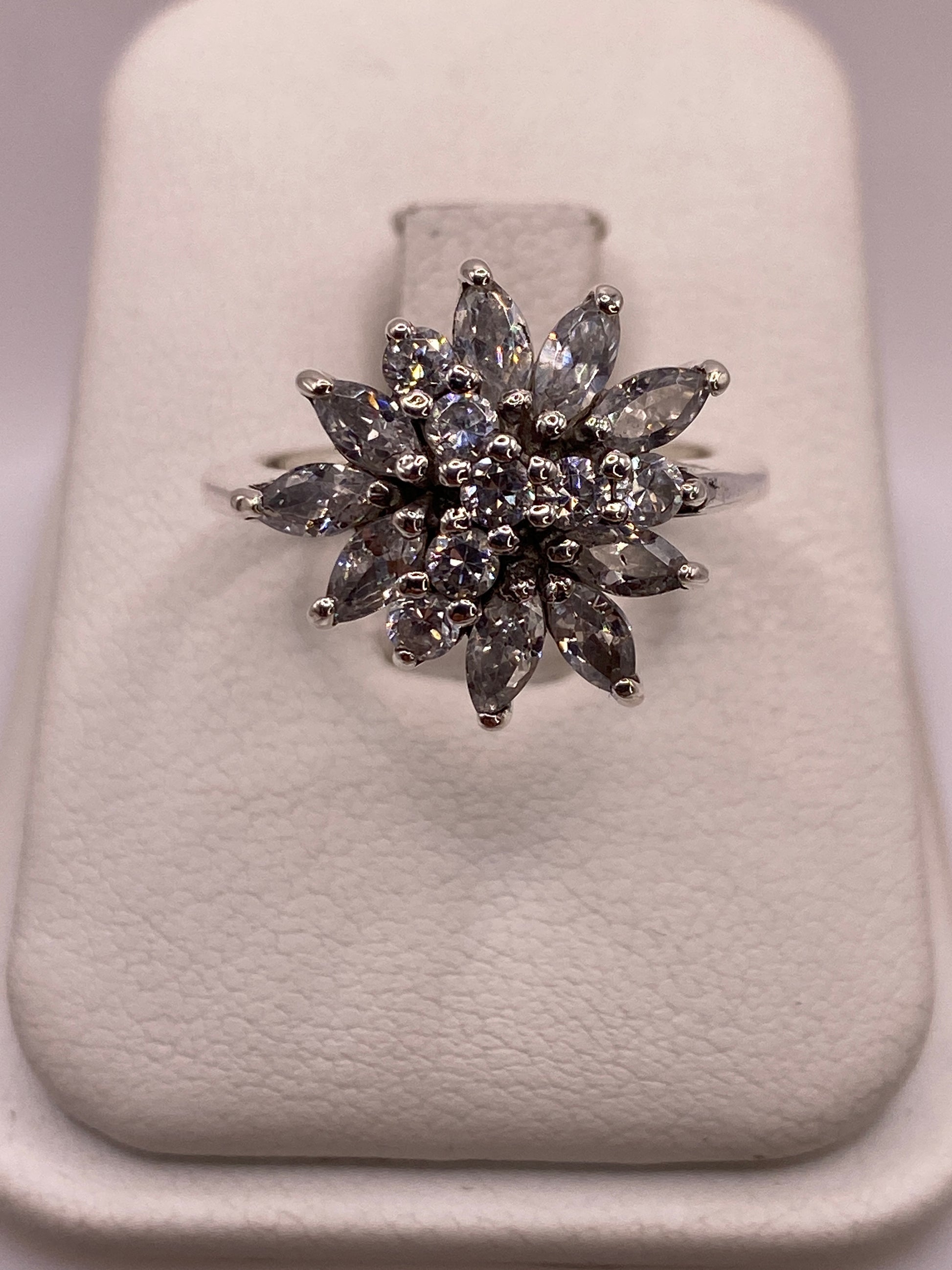 Anillo de plata con flor de circonias blancas visto de frente mostrando el engaste radial