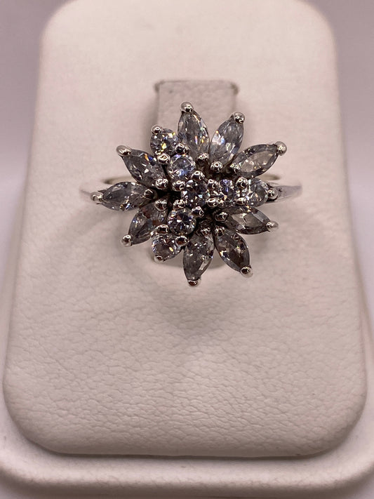 Anillo de plata con flor de circonias blancas visto de frente mostrando el engaste radial