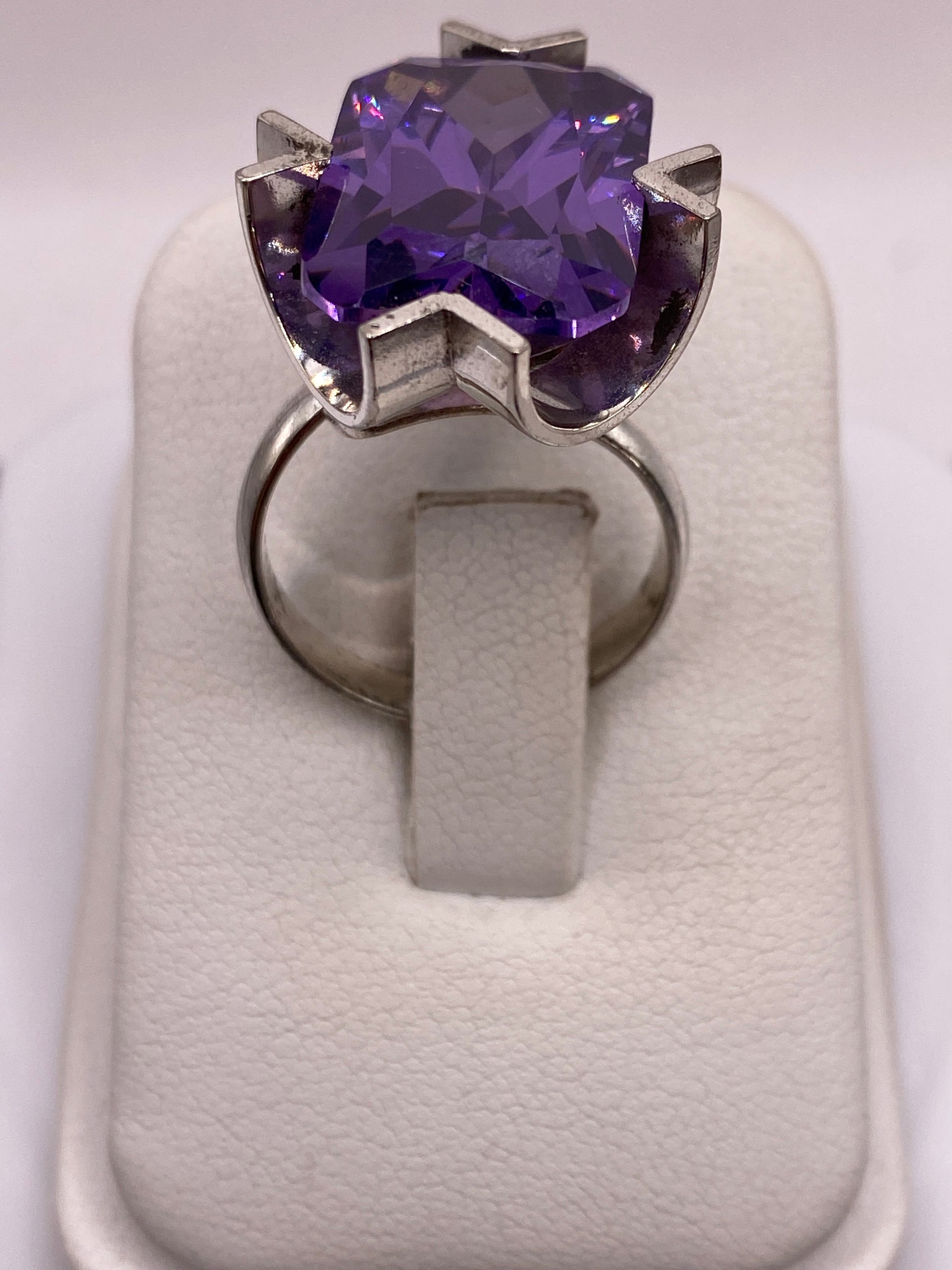 Anillo solitario de plata con circonia púrpura facetada sobre fondo blanco
