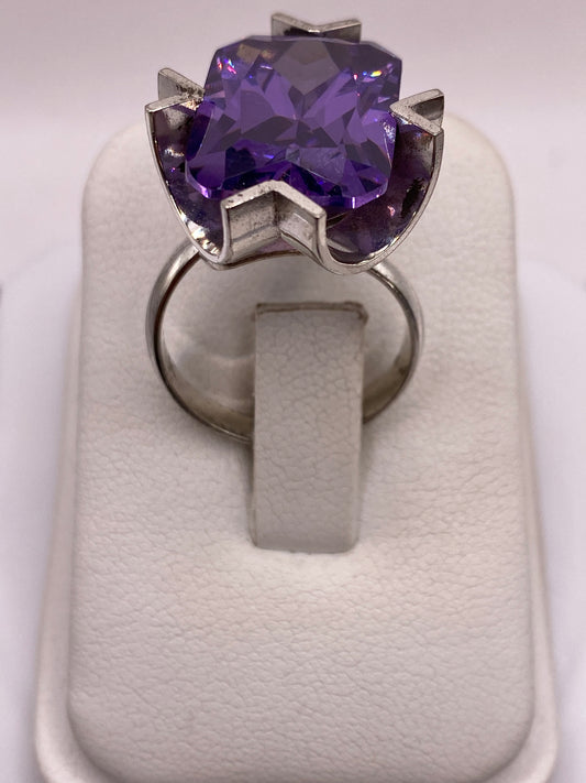 Anillo solitario de plata con circonia púrpura facetada sobre fondo blanco