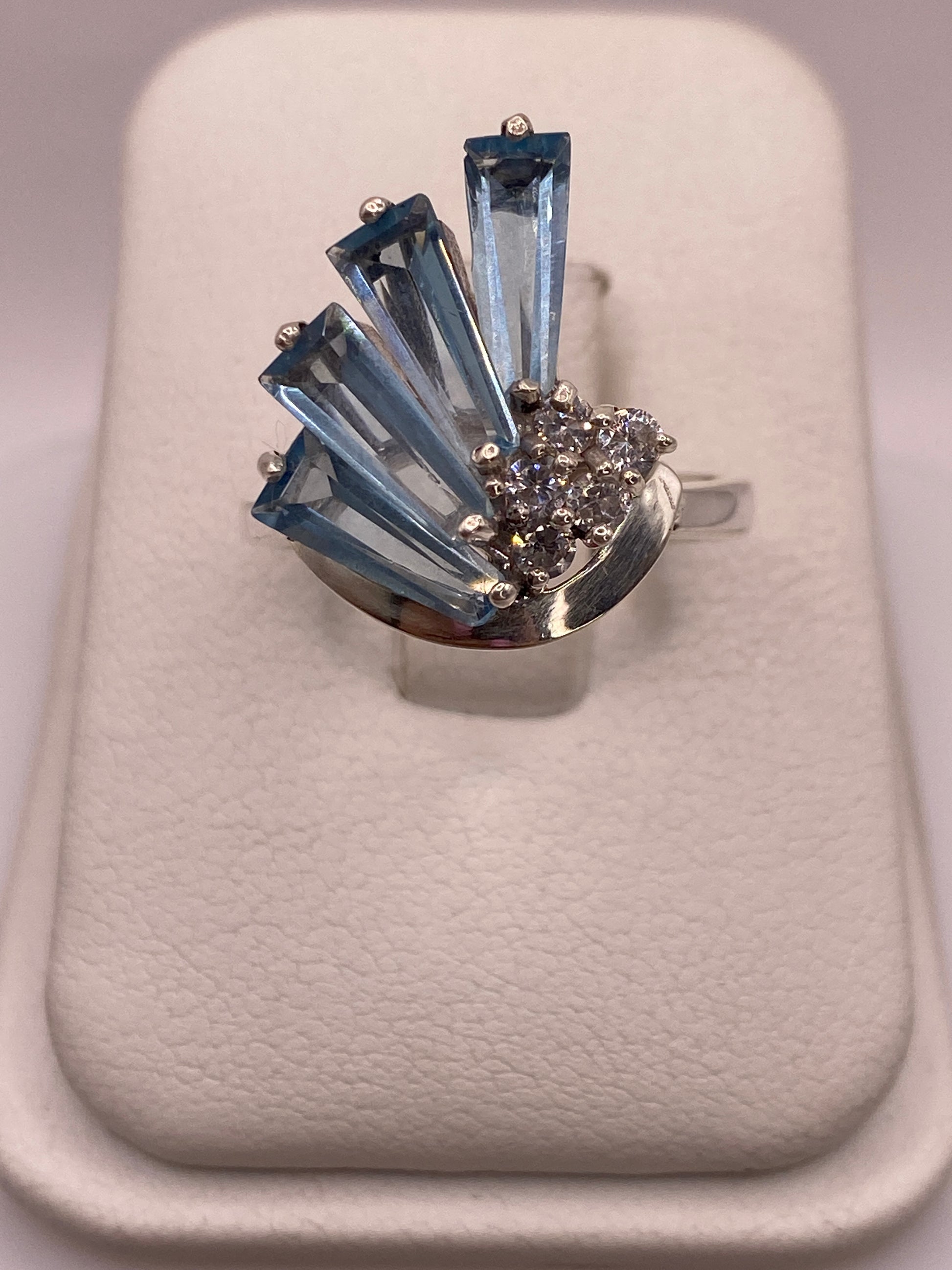 Anillo solitario de plata con circonia azul cielo en estuche blanco, frente con luz natural
