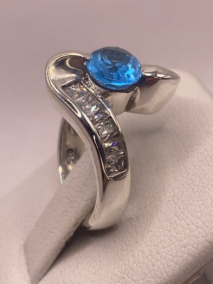 Anillo puesto en mano, circonia azul cielo brillando con fuego diamantino