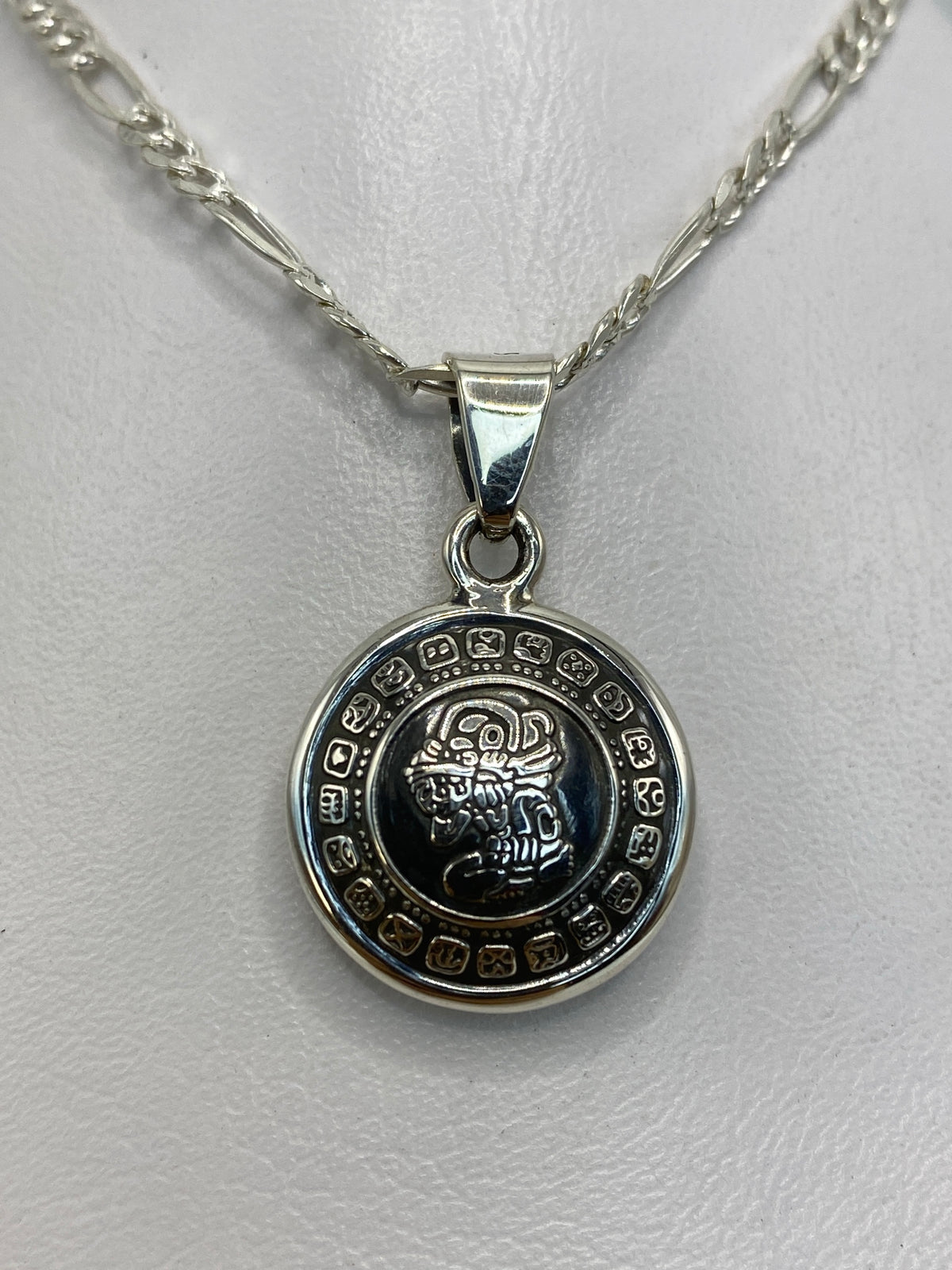Dije de plata con diseño del calendario azteca prehispánico, vista frontal clara