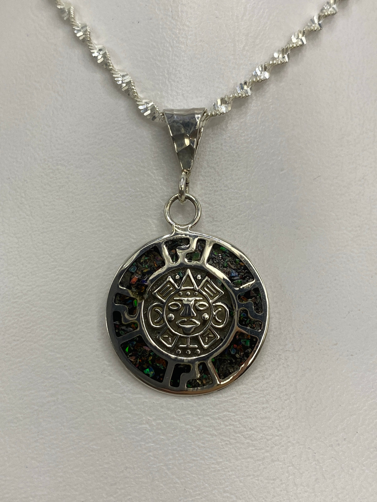 Dije de plata con cara del sol azteca y ópalo de fuego multicolor sobre fondo blanco