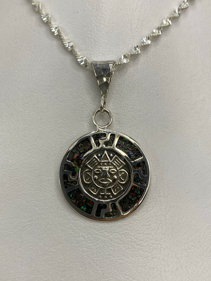 Dije de plata con cara del sol azteca y ópalo de fuego multicolor sobre fondo blanco
