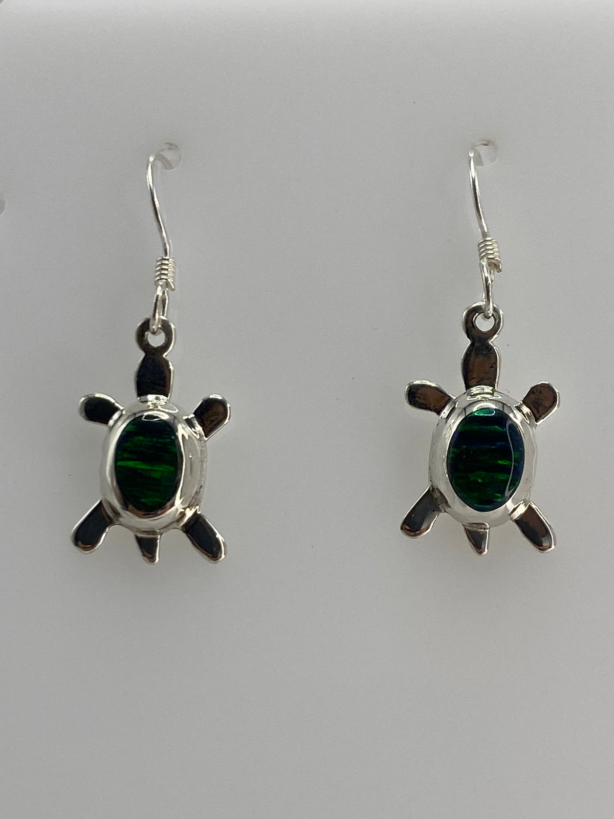 Detalle de arete de tortuga con ópalo verde engastado en plata, vista frontal