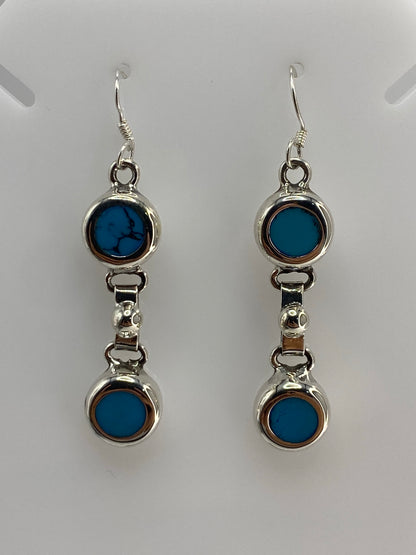 Detalle frontal de los aretes mostrando la turquesa azul y el engaste a mano en plata 925