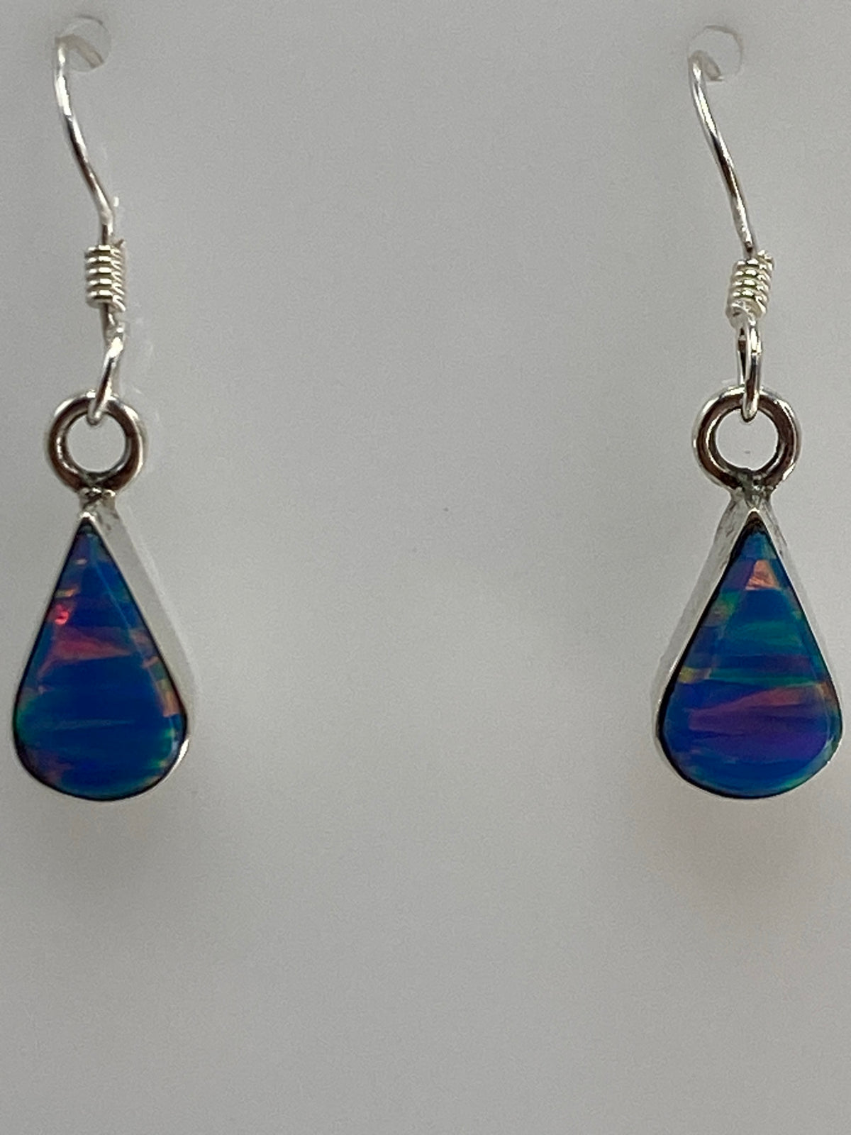 Aretes de plata colgando del gancho, vista frontal del par completo