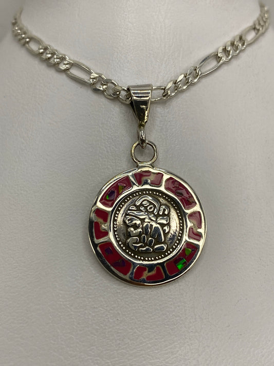 Dije de plata con motivo prehispánico y ópalo de fuego rosa, colgando de cadena figaro