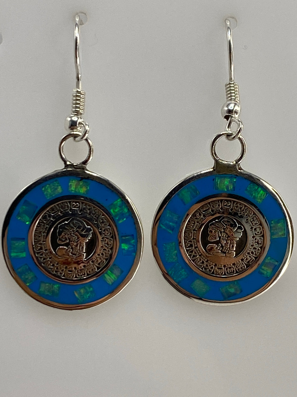 Aretes de plata con ópalo de fuego azul engastados a mano, vistos de frente mostrando el color azul profundo