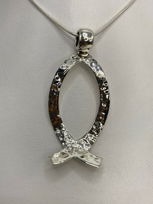 Dije de plata 925 en repujado con diseño de sello prehispánico, colgando de una cadena plateada