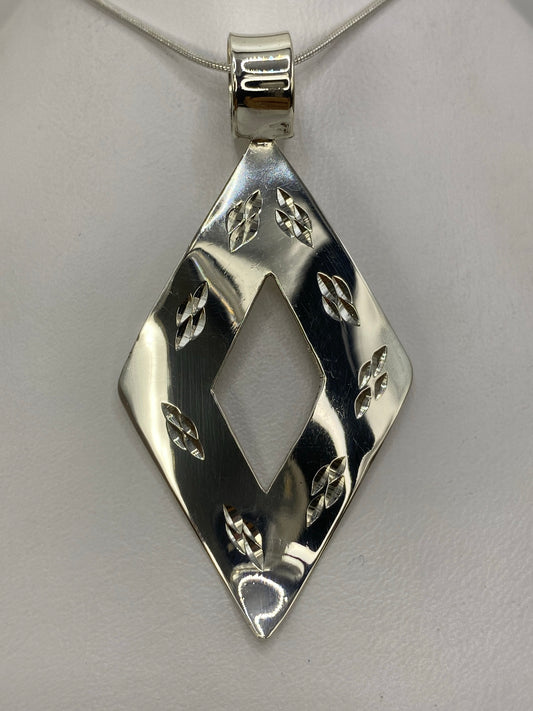 Dije de plata 925 con forma de rombo geométrico calado, colgando de una cadena de plata