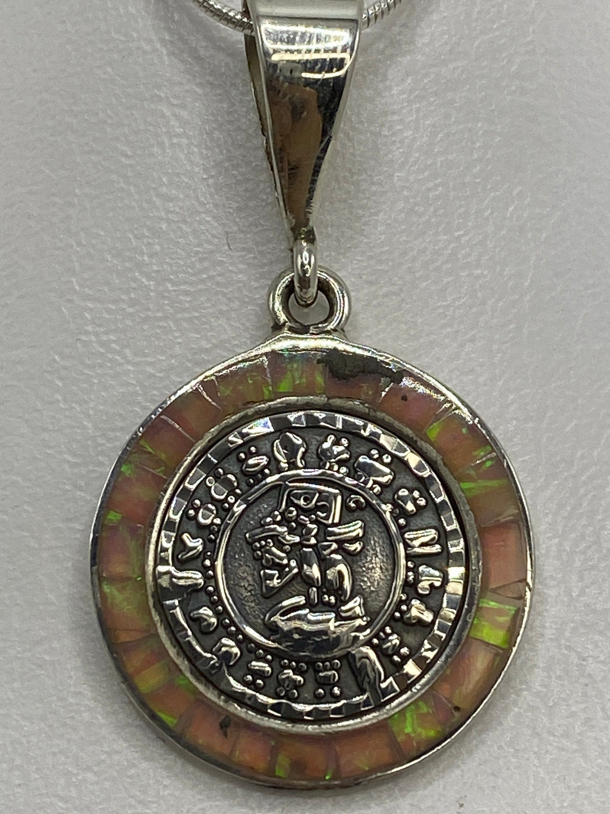 Detalle del nácar verde y marrón incrustado en la circunferencia del dije