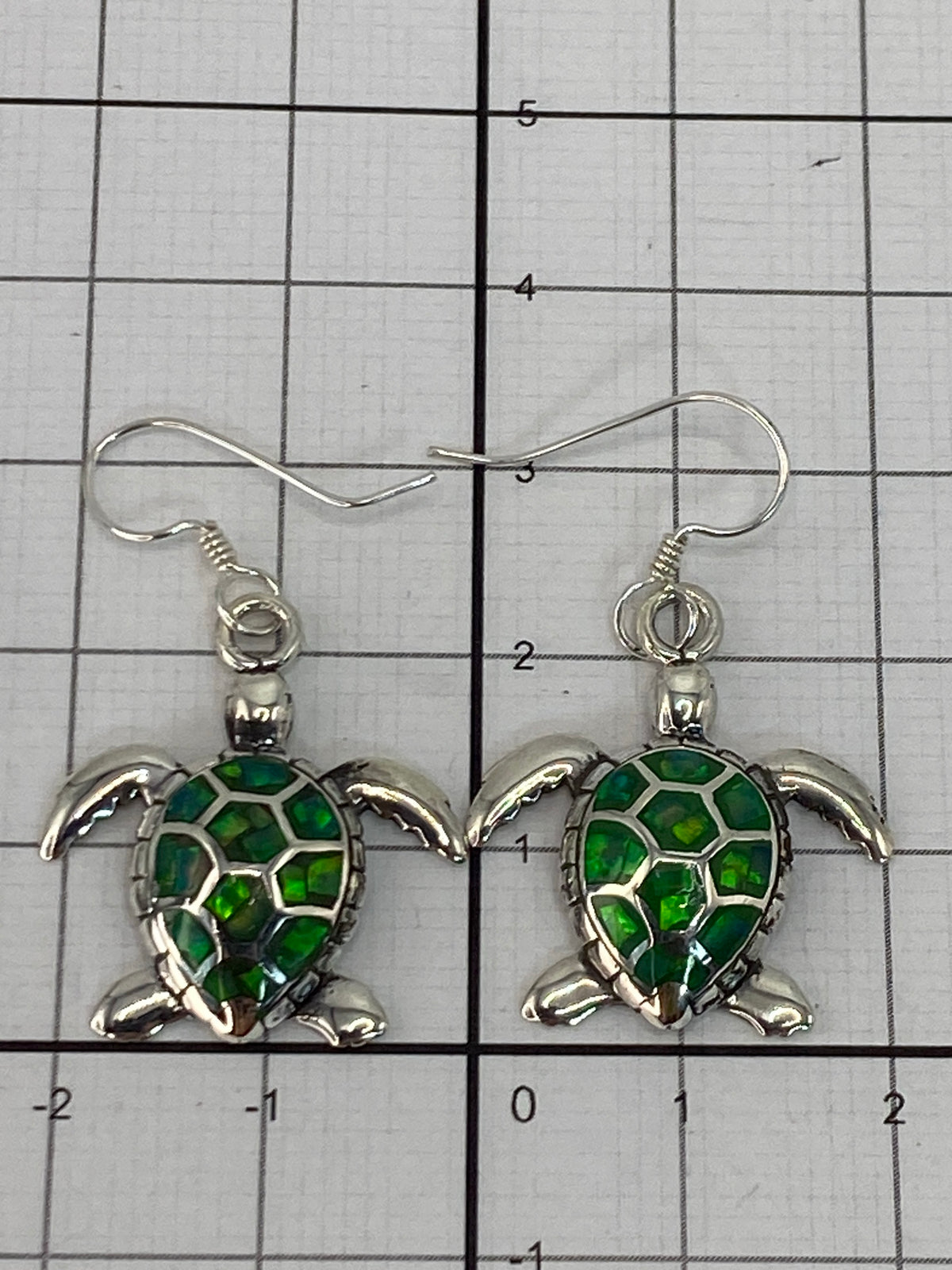 Aretes de plata 950 sobre fondo oscuro iluminando el brillo verde del Ópalo de Fuego