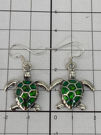 Aretes de plata 950 sobre fondo oscuro iluminando el brillo verde del Ópalo de Fuego