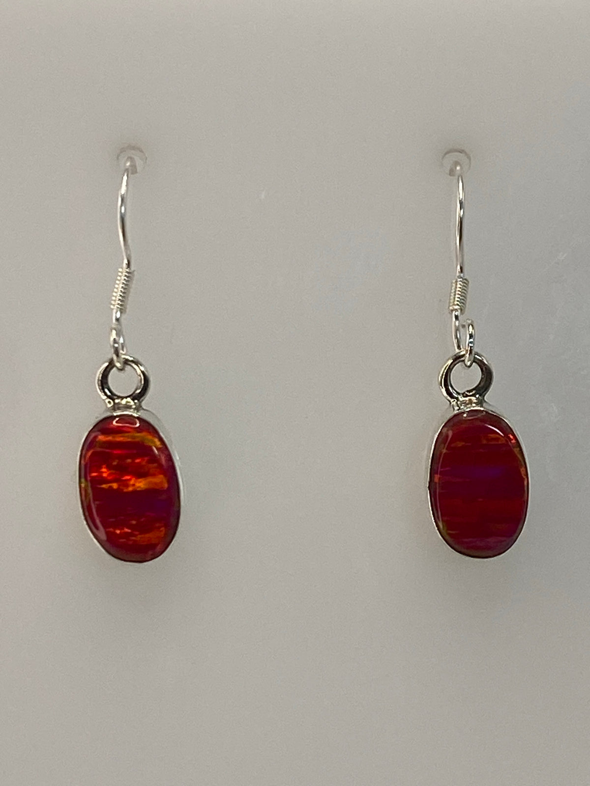 Par de aretes de plata 950 con ópalo de fuego rosa colgando sobre fondo blanco