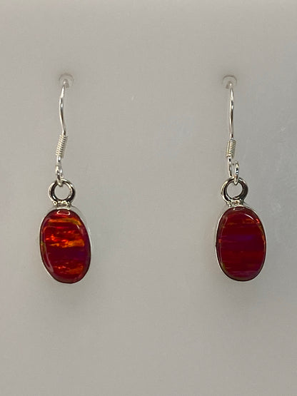 Par de aretes de plata 950 con ópalo de fuego rosa colgando sobre fondo blanco