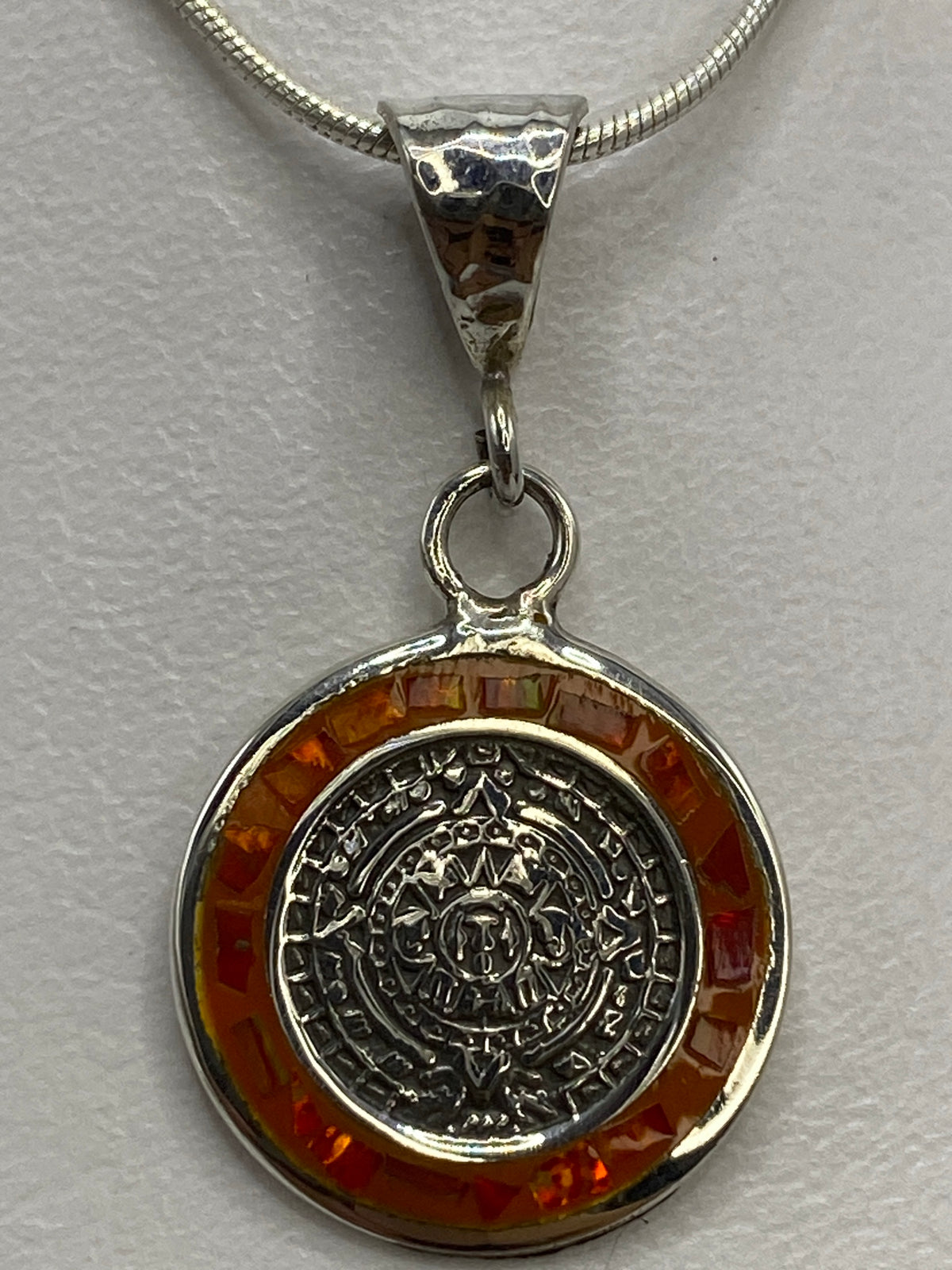 Dije de 3 cm sobre regla de medición mostrando el tamaño exacto del Calendario Azteca